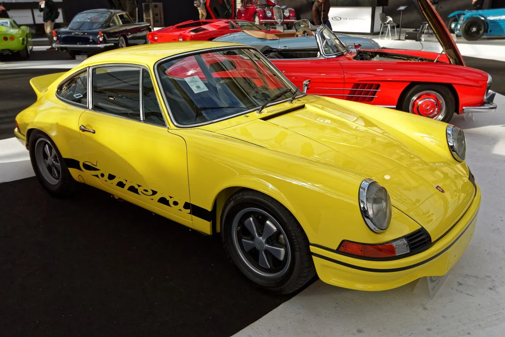 Yellow 1973 Porsche 911 Carrera RS 2.7 Sport Lightweight (M471) with black Carrera side script, front three-quarter view
