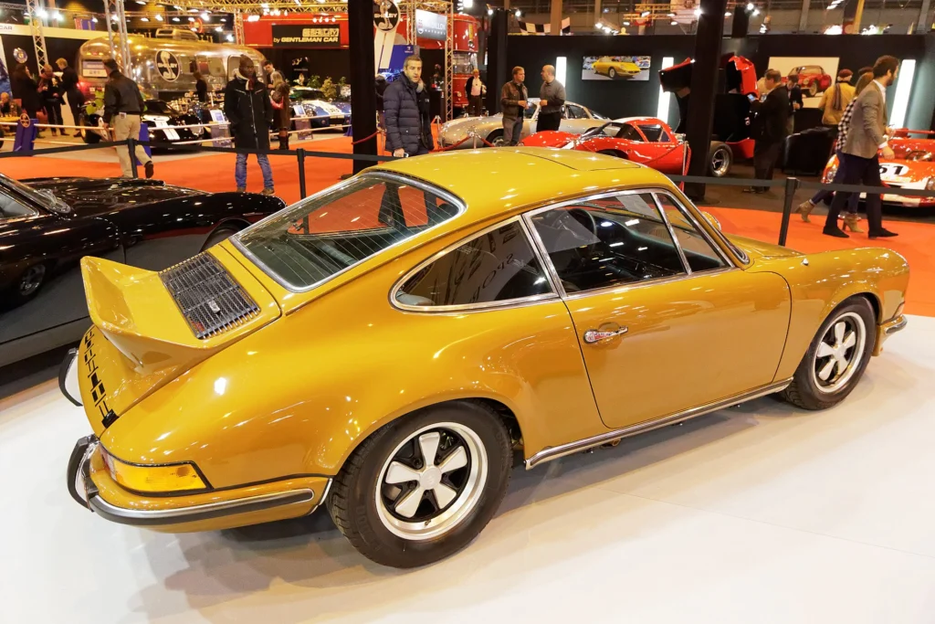 Gold 1973 Porsche 911 Carrera RS 2.7 Touring seen from the rear quarter, showing the ducktail spoiler