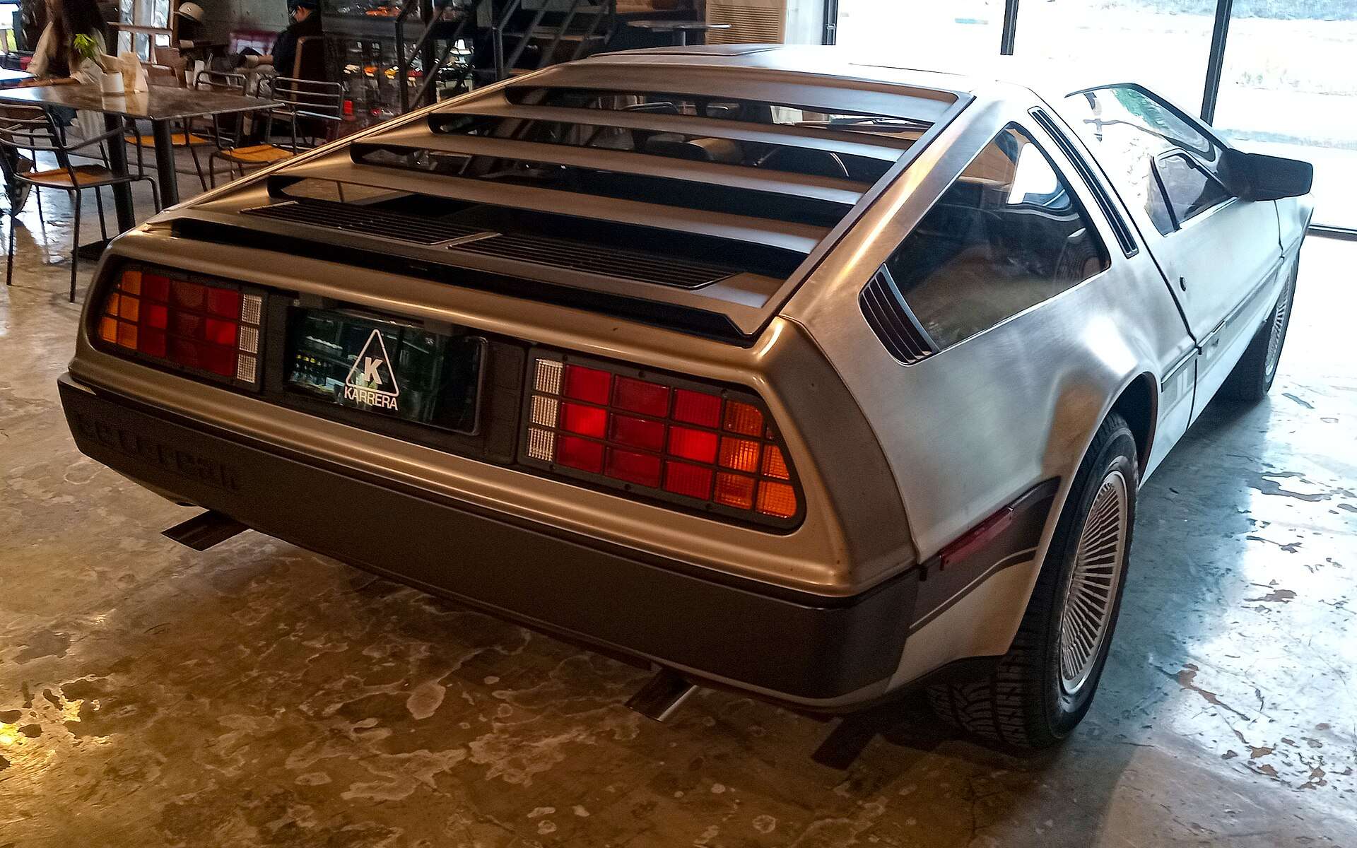 Rear three-quarter view of a DeLorean DMC-12 showing the louvered engine cover and brushed stainless panels