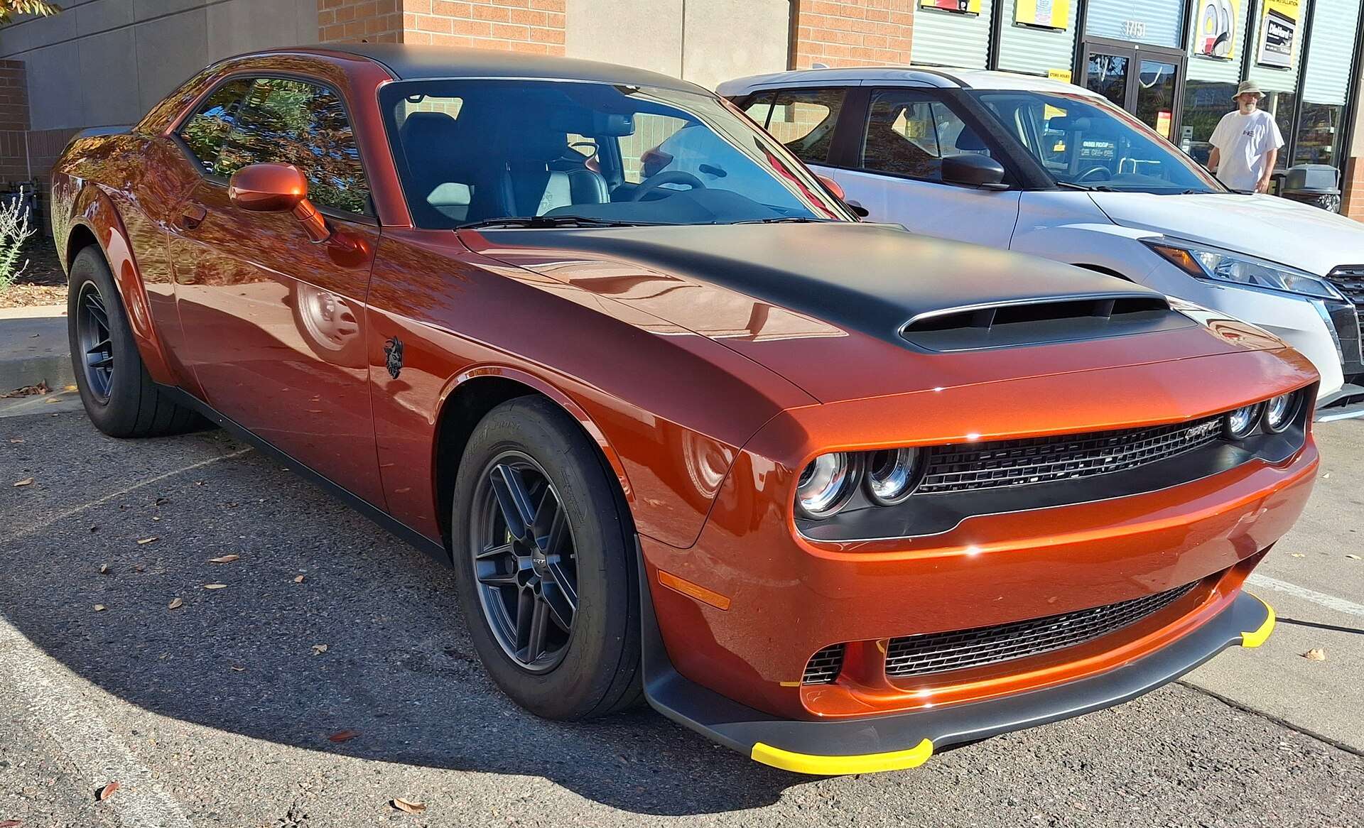 Orange 2023 Dodge Challenger SRT Demon 170 with a black hood graphic parked at the curb, front three-quarter view
