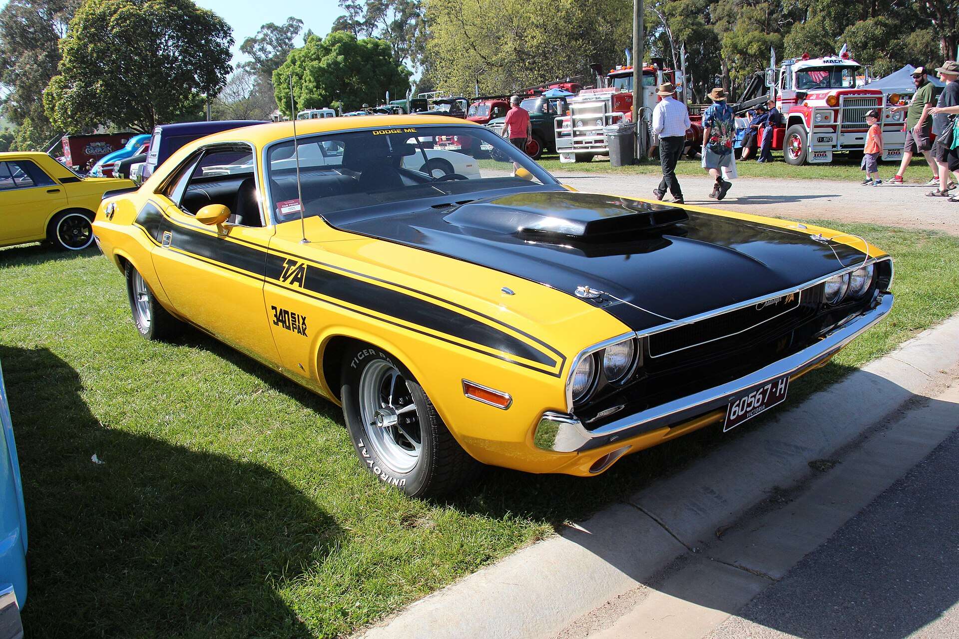 Yellow 1970 Dodge Challenger T/A 340 with black hood and side stripes at a car show