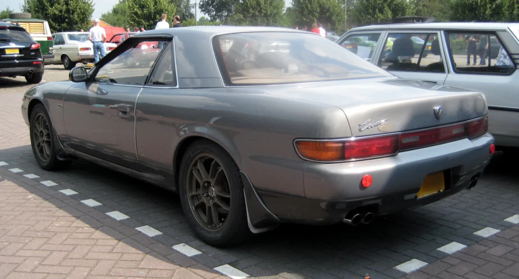 Rear three-quarter view of a grey Eunos Cosmo showing its full-width taillamp panel and twin exhaust tips