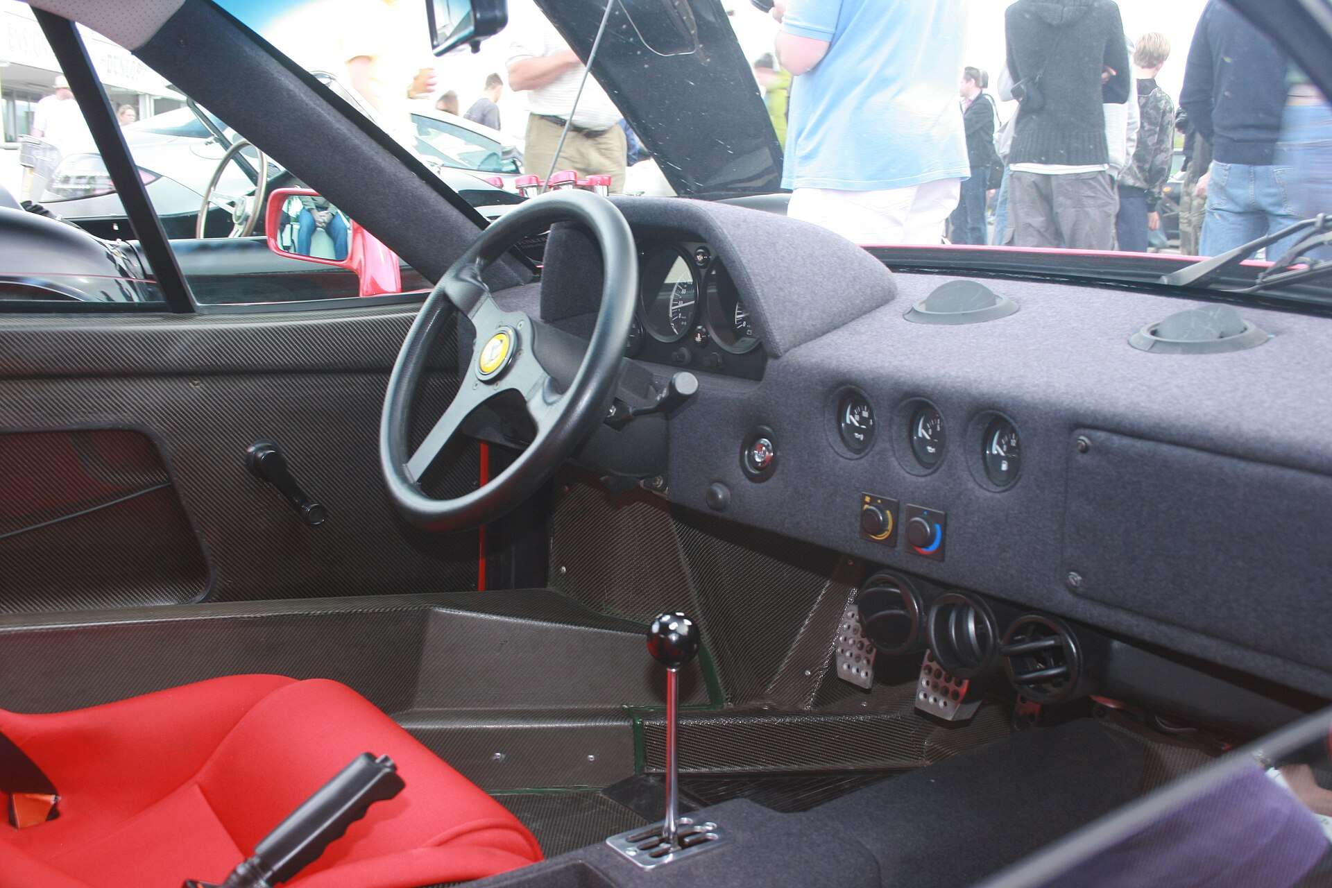 Spartan cloth-trimmed interior of a Ferrari F40 with exposed door pull and bare floor