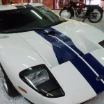 Ford GT spec sheet photo: white 2005 Ford GT with blue center stripes, front three-quarter view