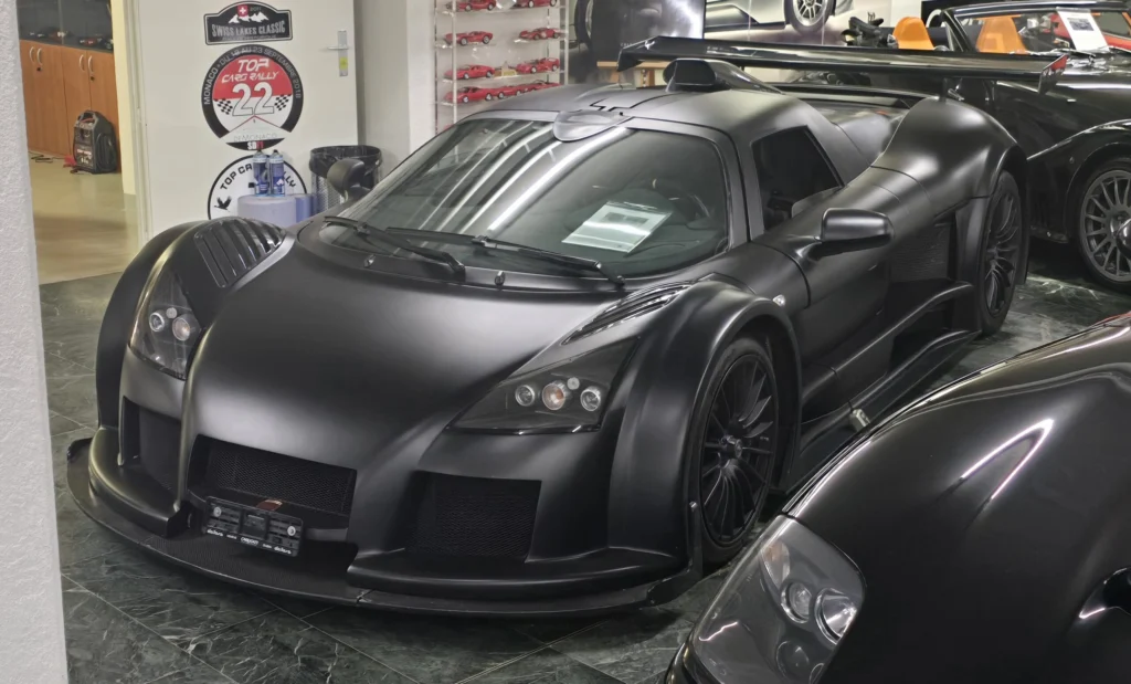 Matte black Gumpert Apollo Sport supercar parked indoors in a showroom