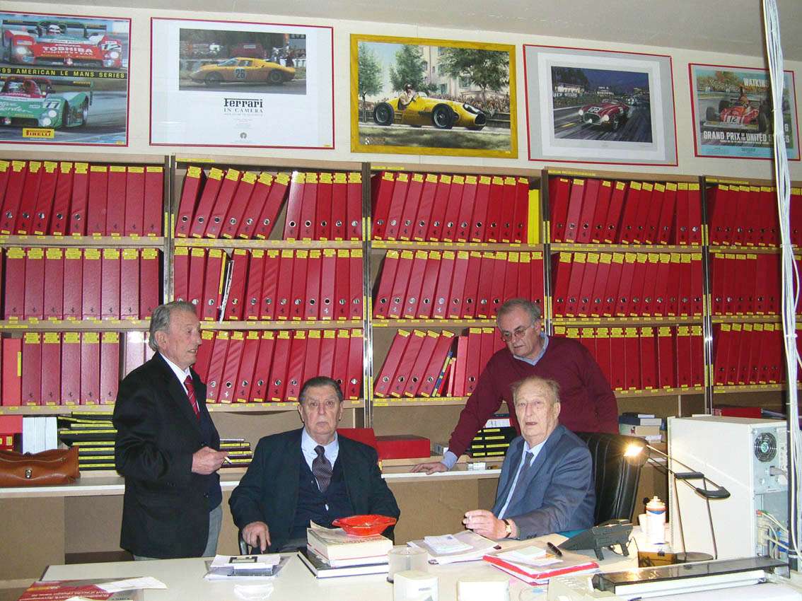 Four Ferrari figures standing together at Garage Francorchamps in 2005, including Jacques Swaters, Sergio Scaglietti and Franco Gozzi