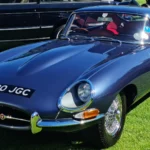 Blue 1962 Jaguar E-Type Series 1 fixed-head coupe parked on grass at a concours