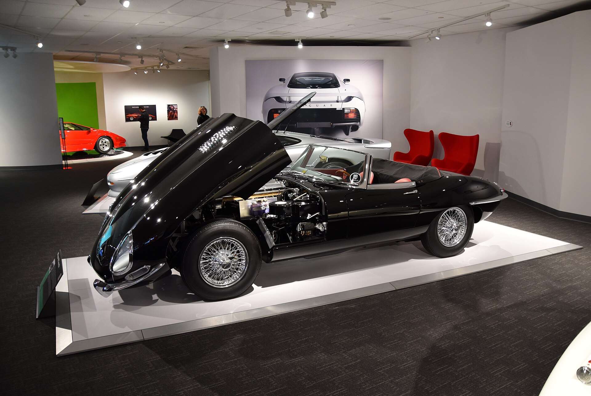 Black 1963 Jaguar E-Type Series 1 roadster with its one-piece bonnet raised on a museum display