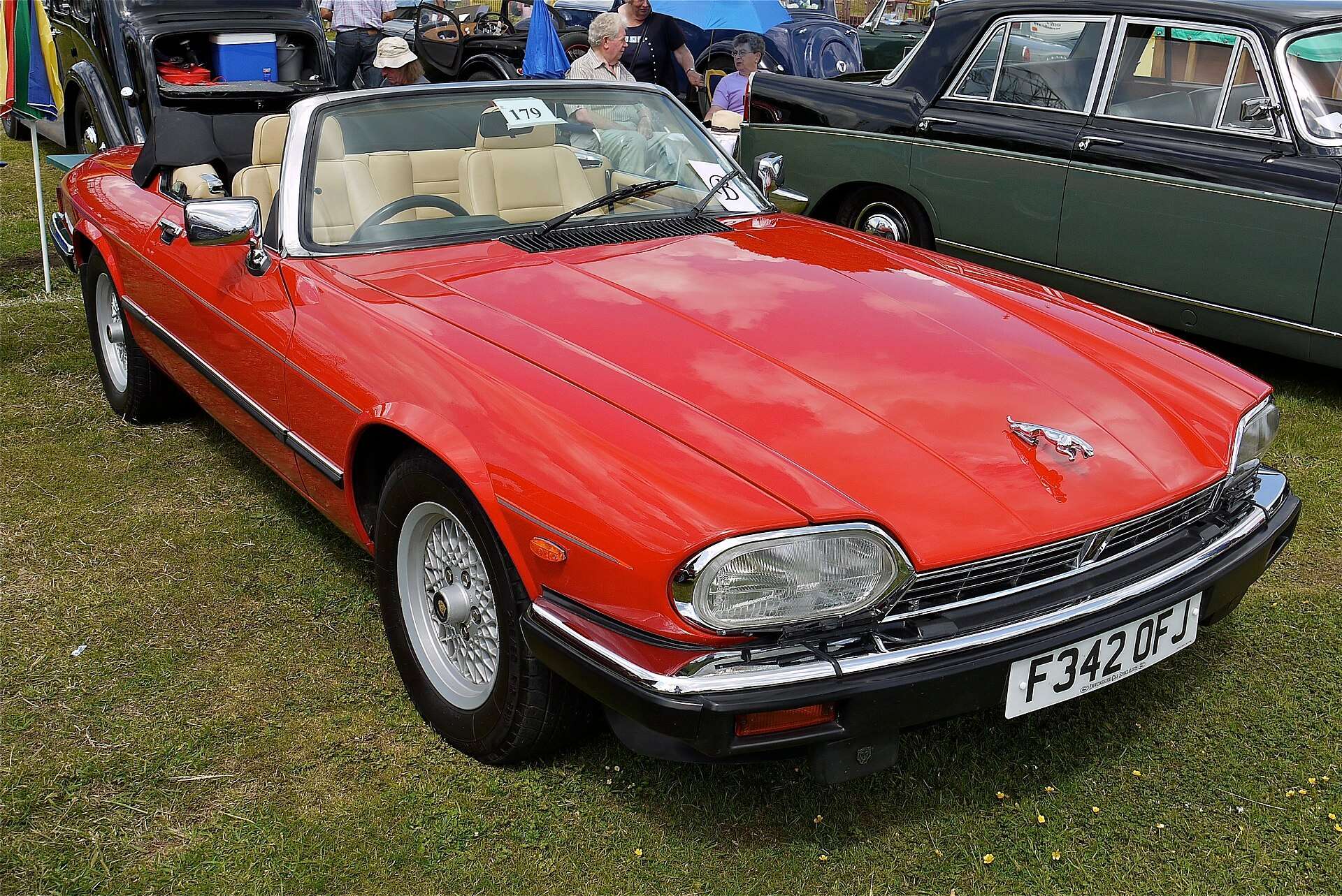 Red 1988 Jaguar XJ-S V12 convertible with the top down at a car show, front three-quarter view