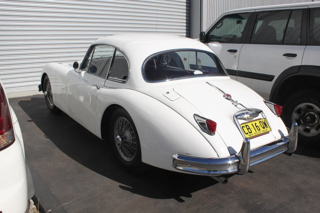 White 1958 Jaguar XK150 fixed-head coupe seen from the rear with wire wheels