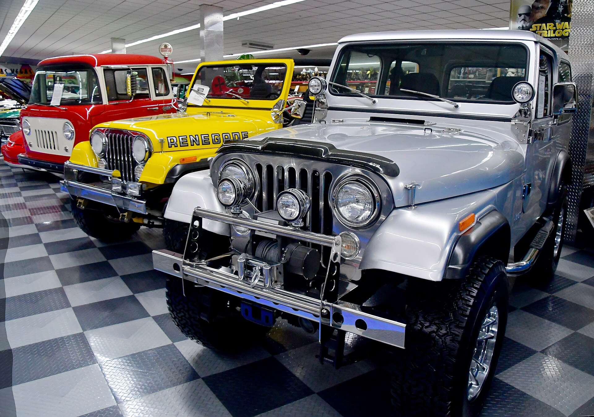 Silver 1981 Jeep CJ-7 Renegade displayed on a checkered showroom floor