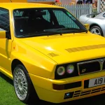 Delta Integrale vs. Escort Cosworth vs. Celica GT-Four: Which Group A Rally Special Is the Smarter Collector Buy? Yellow 1994 Lancia Delta HF Integrale Evoluzione parked on grass at London Concours, front three-quarter view