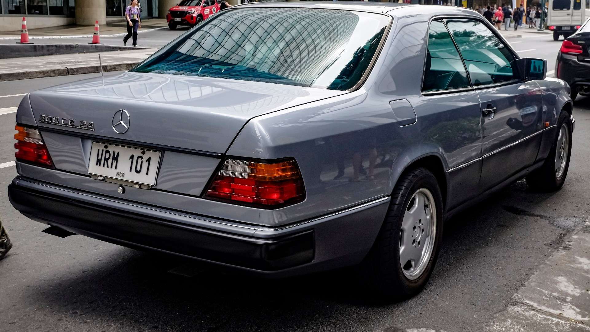 Pearl grey metallic Mercedes-Benz 300 CE-24 coupe from the rear three-quarter with the 300 CE-24 trunk badge