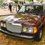 A $252,000 Mercedes Wagon Didn’t Re-Rate the W123. It Priced One Car. Burgundy 1983 Mercedes-Benz 300 TD Turbo S123 station wagon parked on grass at a car show, seen from the front three-quarter