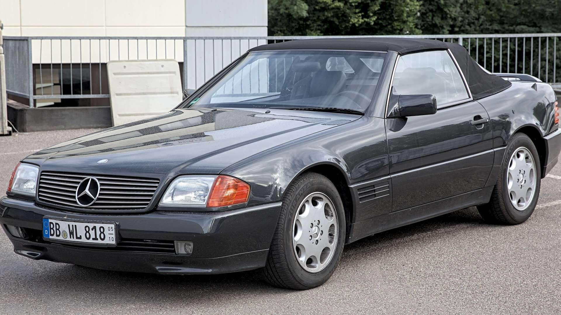 Front three-quarter view of a dark Mercedes-Benz R129 SL roadster showing the headlamps and radiator grille that inspired the front-end swap