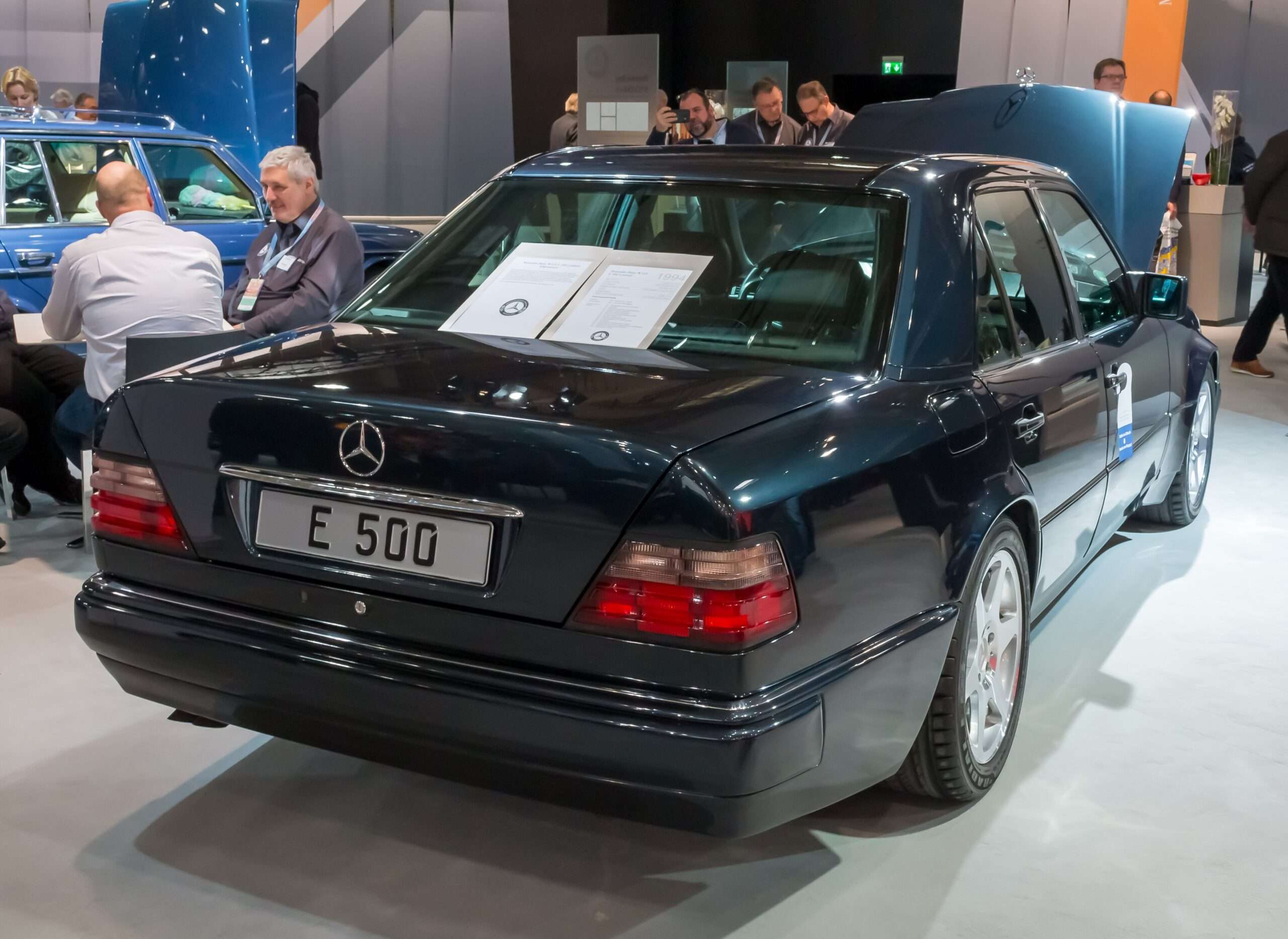 Rear view of a dark green Mercedes-Benz E 500 W124 on display showing the E 500 trunk badge and wide rear fenders