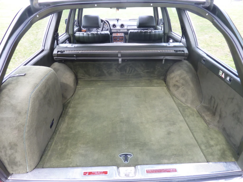 Carpeted cargo area of a 1983 Mercedes-Benz W123 300 TDT wagon seen through the open tailgate, with the rear seat backs visible