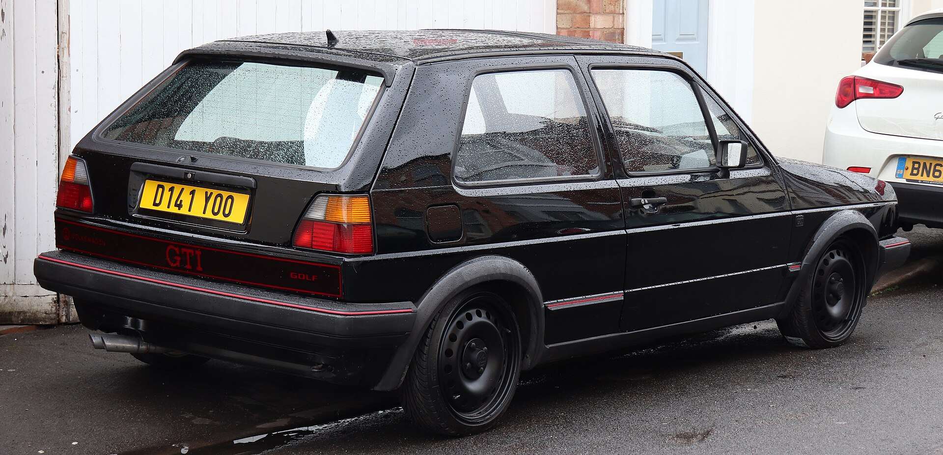 Black 1986 Volkswagen Golf GTI Mk2 three-door hatchback seen from the rear three-quarter with a red GTI badge