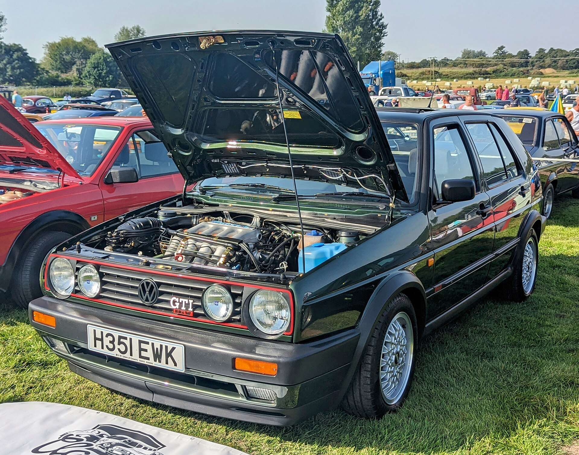 Black 1990 Volkswagen Golf GTI 16V with its hood raised at a car show, showing the 16-valve four-cylinder engine