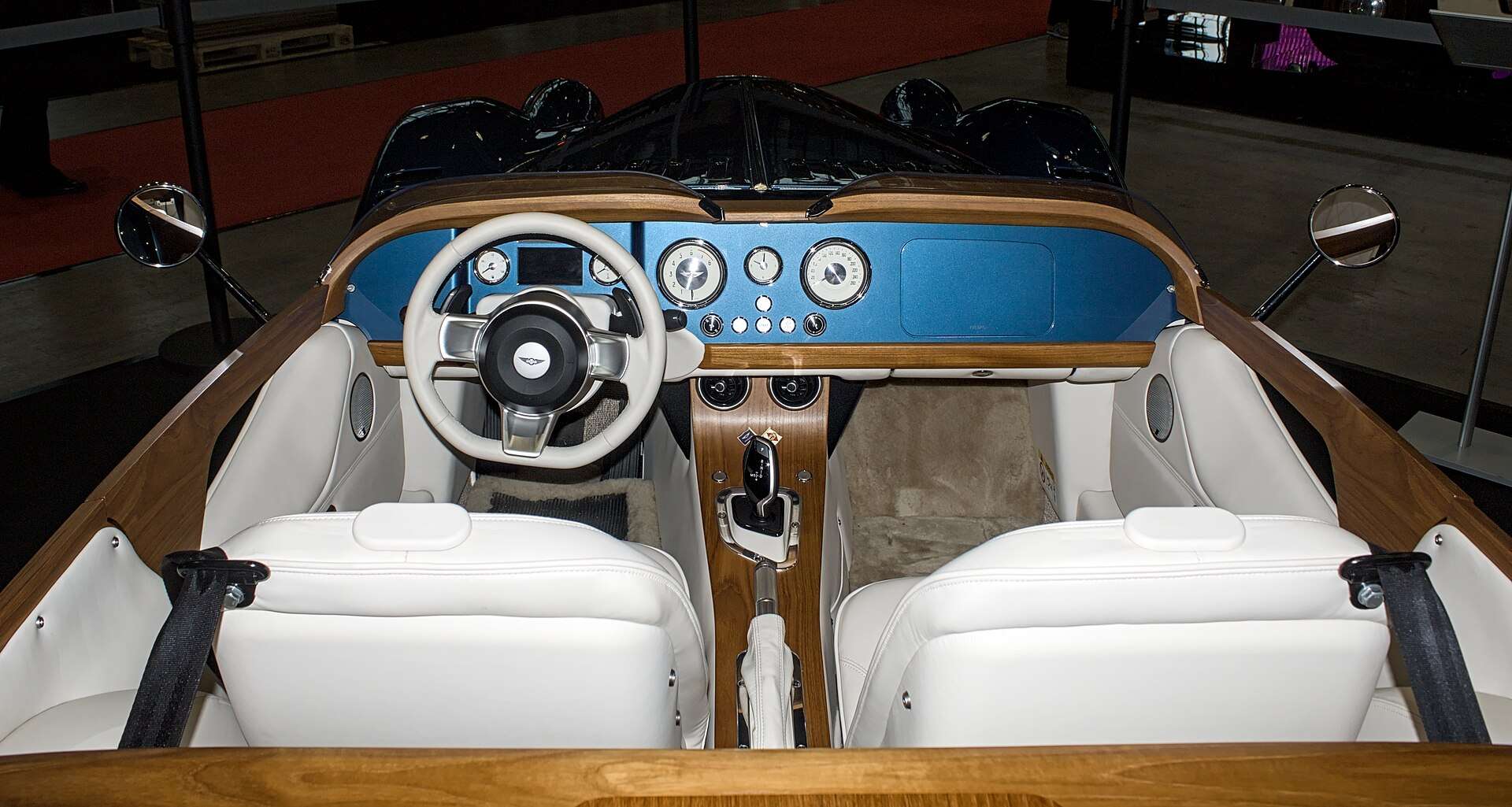 Overhead view of the Morgan Midsummer cockpit with teak trim, blue dashboard and white leather seats