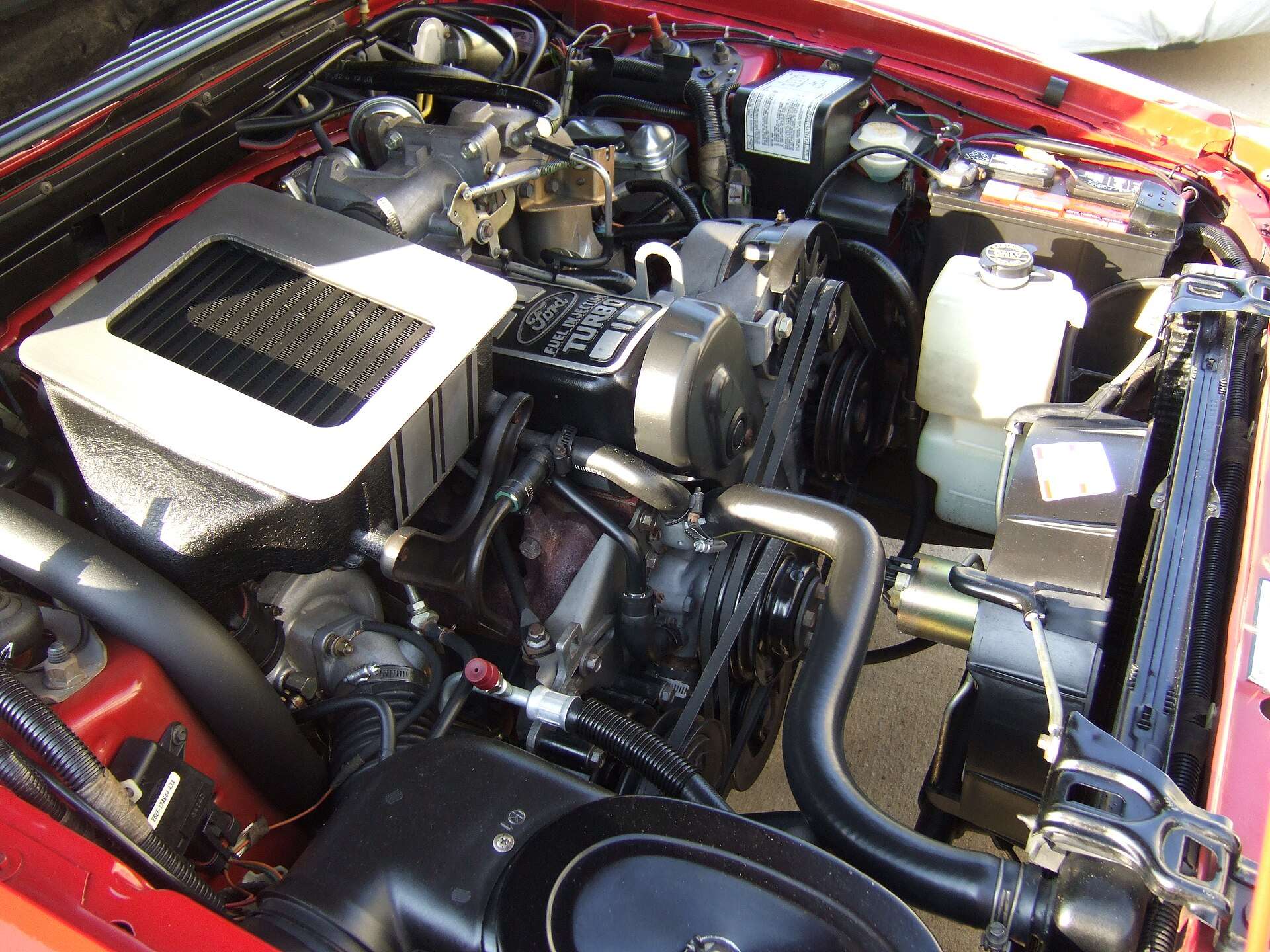 Engine bay of a 1986 Ford Mustang SVO showing the 2.3-liter turbocharged four-cylinder and air-to-air intercooler