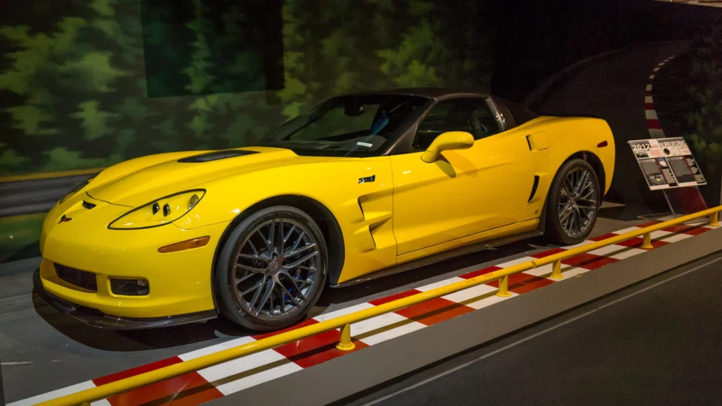 Yellow C6-era Corvette coupe on a display platform styled like a racetrack curb at the National Corvette Museum