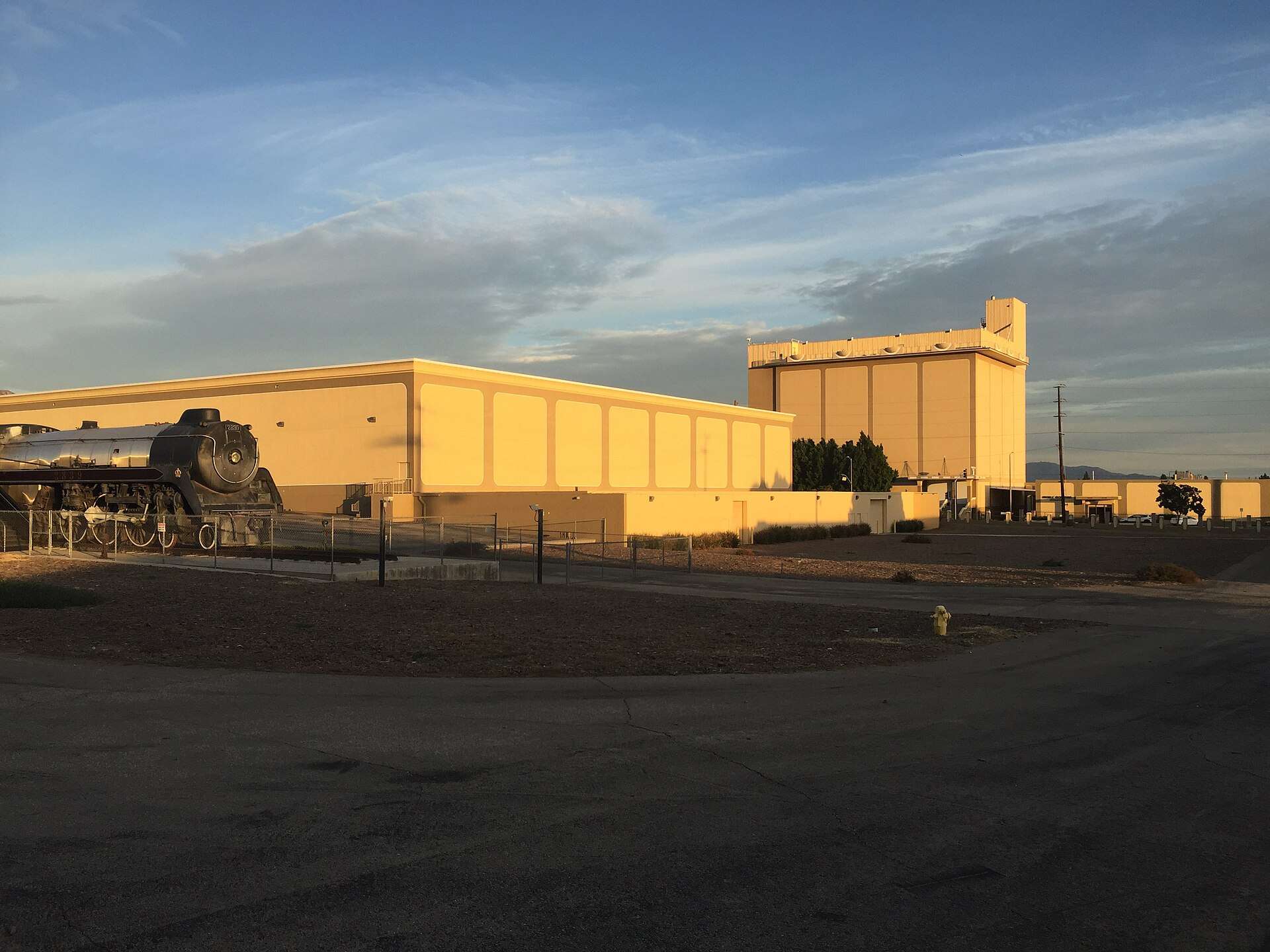 Exterior view of the Nethercutt Collection complex in Sylmar, California, with the museum buildings and an outdoor steam locomotive display
