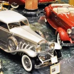The Nethercutt Collection Was Built in a Restoration Shop, Not a Showroom One-off 1933 Duesenberg SJ Arlington Torpedo Sedan known as Twenty Grand beside a red 1934 Packard LeBaron Sport Phaeton at the Nethercutt Collection