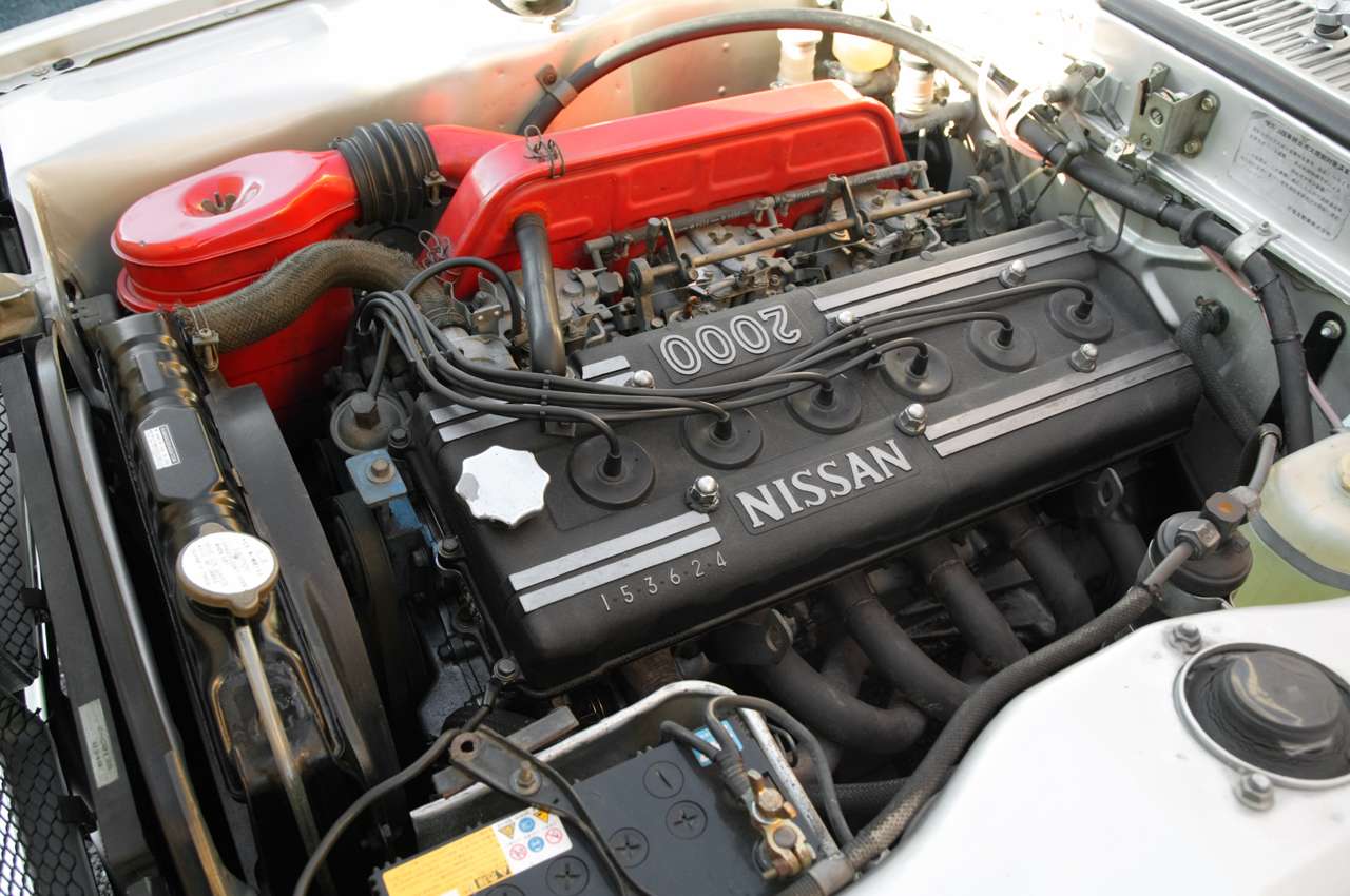 Nissan S20 DOHC inline-six in a KPGC10 Skyline GT-R engine bay with red air cleaner, side-draft carburetors and Nissan 2000 cam cover