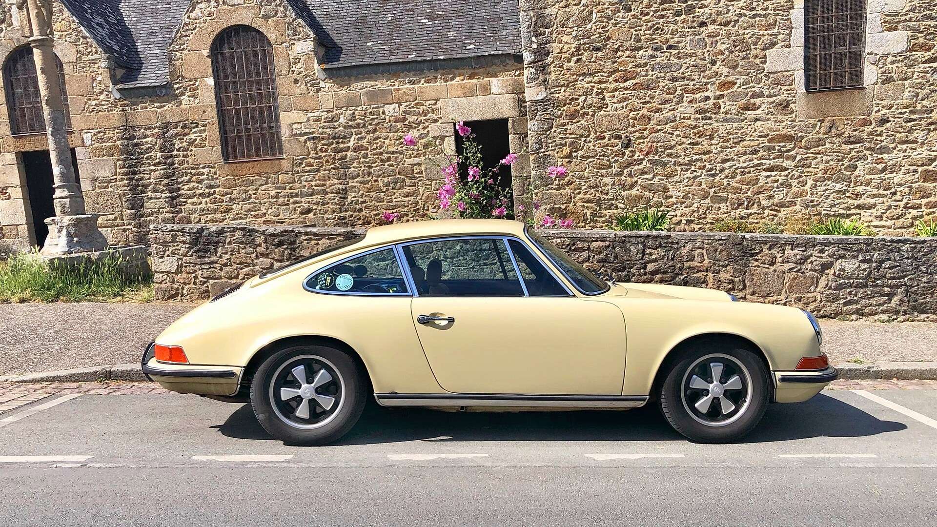 Light ivory 1973 Porsche 911 T 2.4 in right-side profile showing its Fuchs alloy wheels