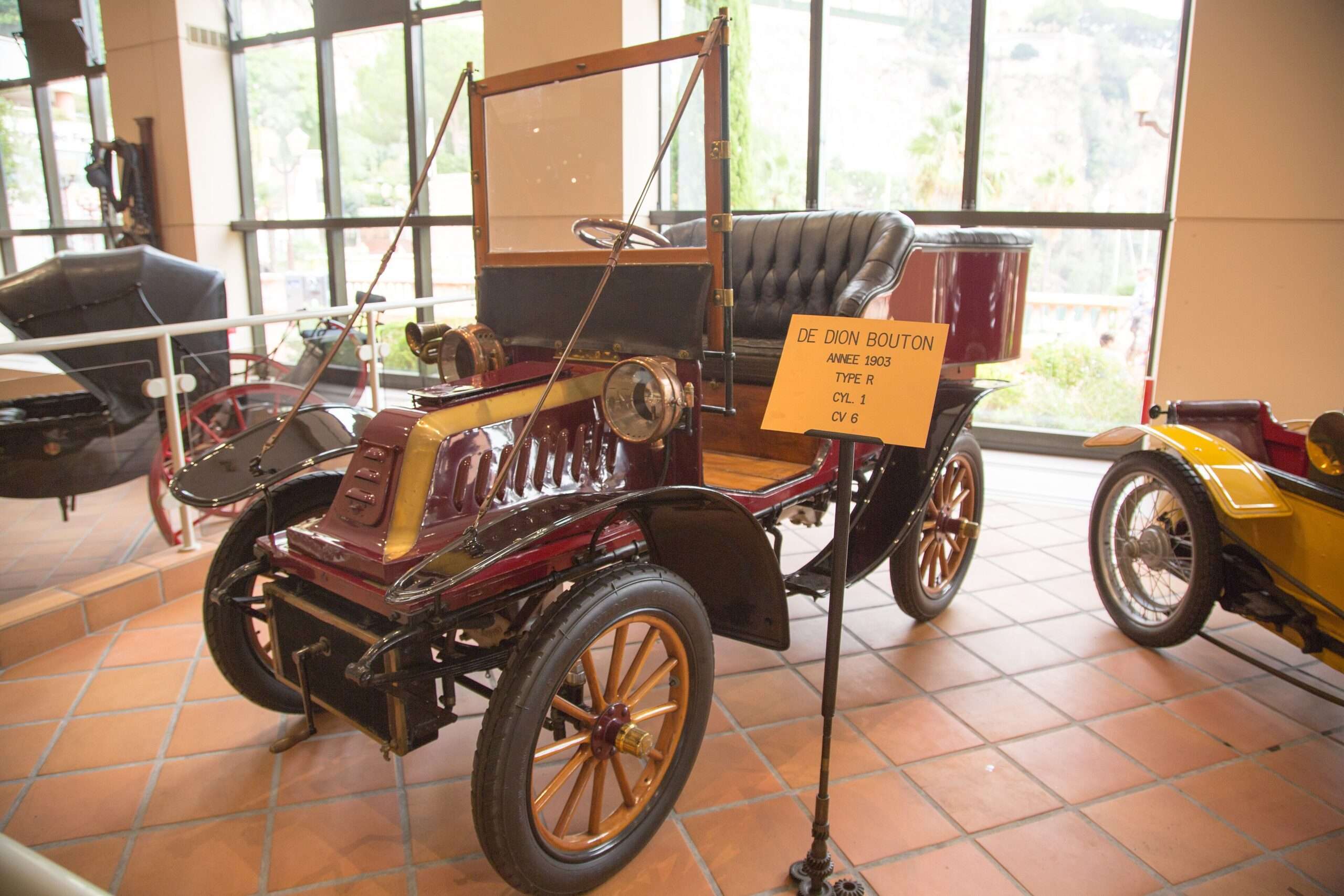 Maroon 1903 De Dion-Bouton Type R open tourer with brass trim on the tiled floor of the Monaco Top Cars Collection