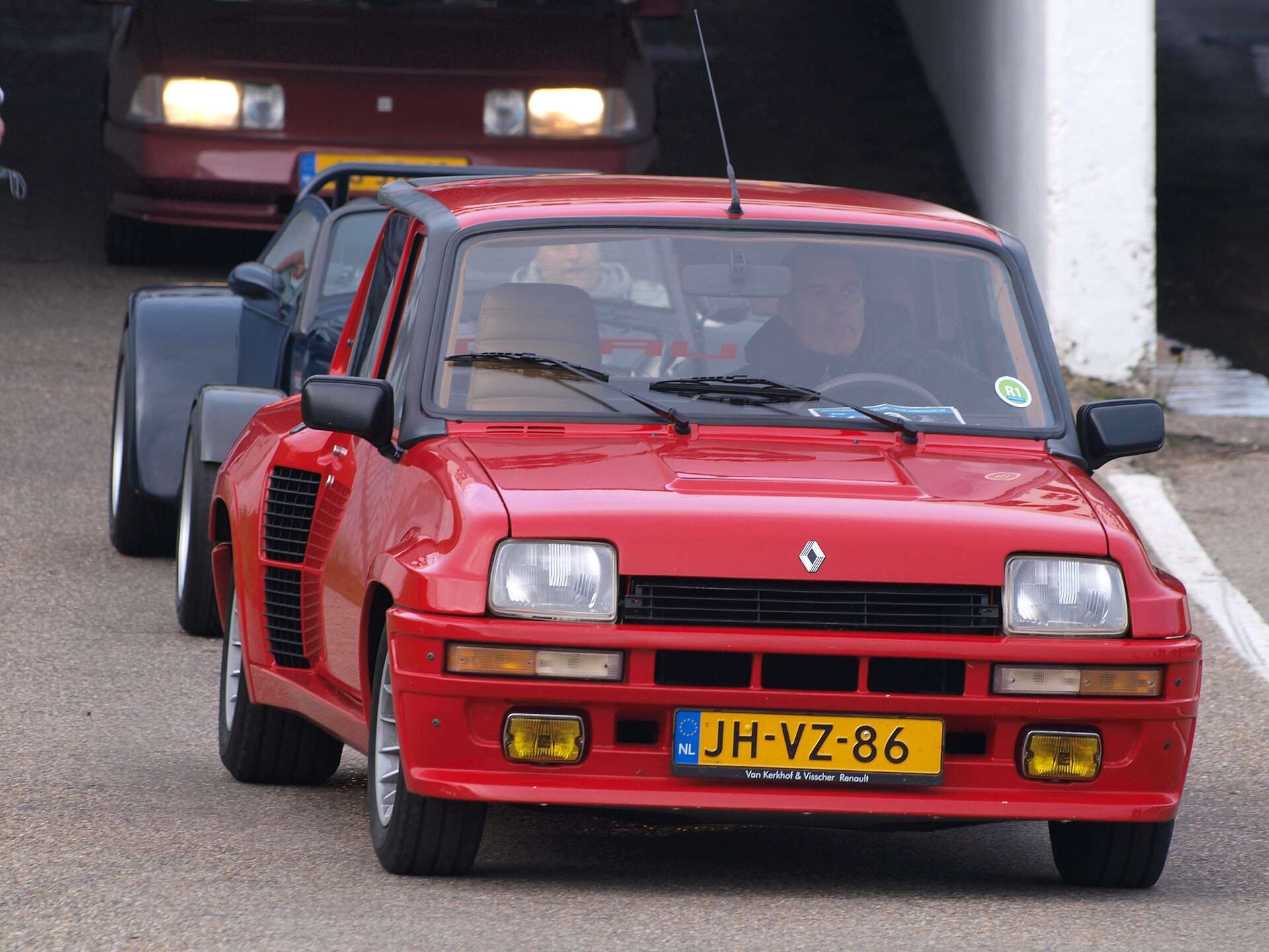 Red 1981 Renault 5 Turbo 1 seen head-on at a classic car festival, with other cars parked behind it