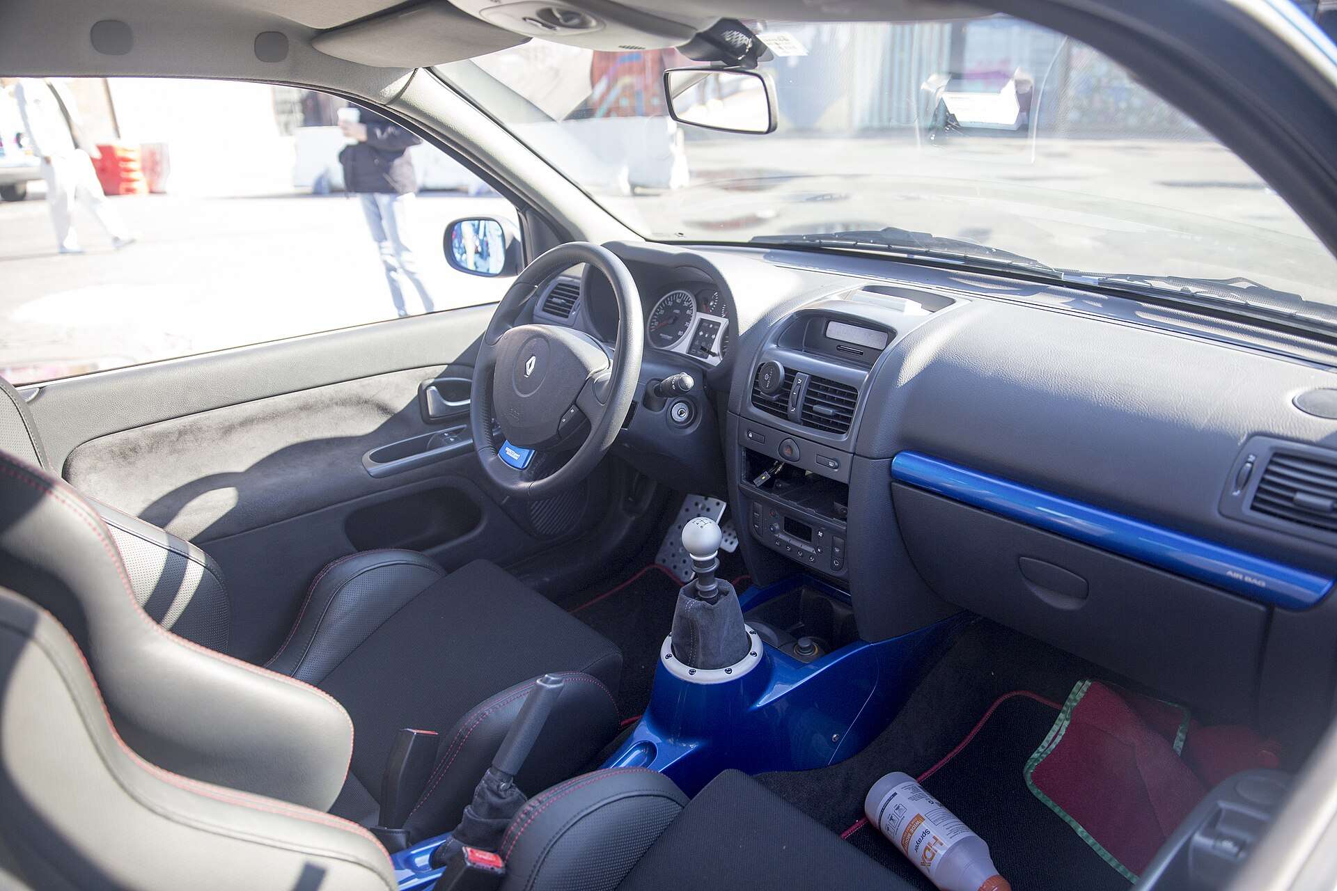 Interior of a Renault Clio V6 showing a blue-trimmed dashboard, six-speed shift lever and sport seats