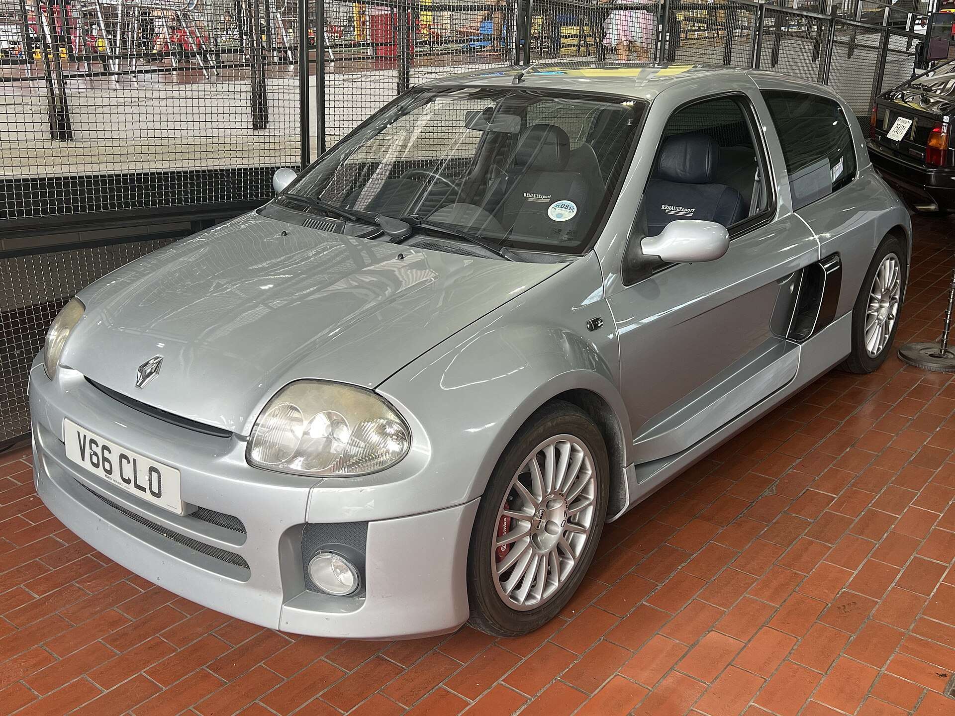 Silver 2002 Renault Clio V6 Phase 1 with side air intakes parked on a brick floor at the Lane Motor Museum