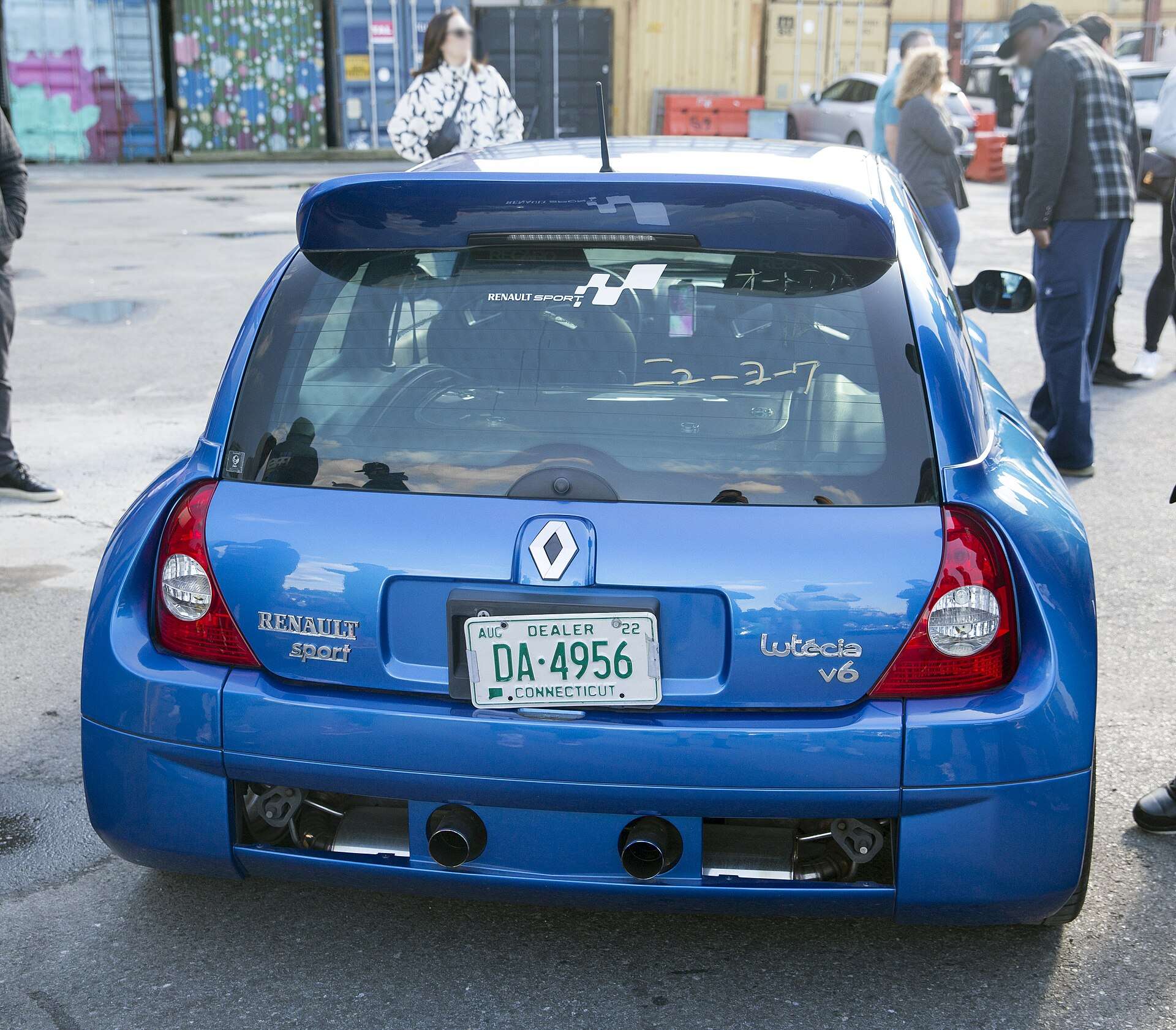 Rear view of a blue Renault Clio V6 showing the widened tail, Lutécia V6 badge and twin exhaust outlets