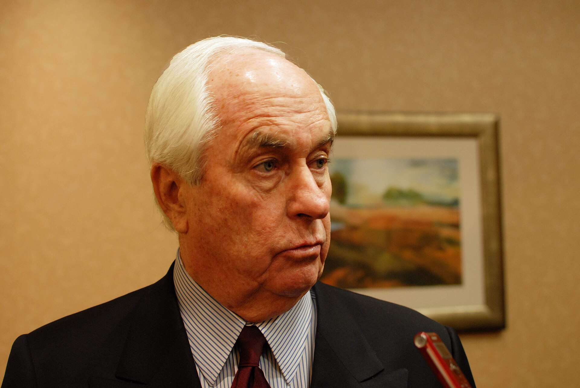 Roger Penske, white-haired, in a suit and tie, speaking at a 2010 National Motorsports Press Association event