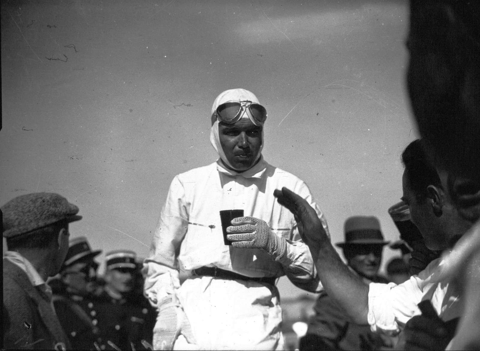 Black-and-white photograph of Mercedes-Benz driver Rudolf Caracciola in white racing overalls and goggles at the 1935 French Grand Prix