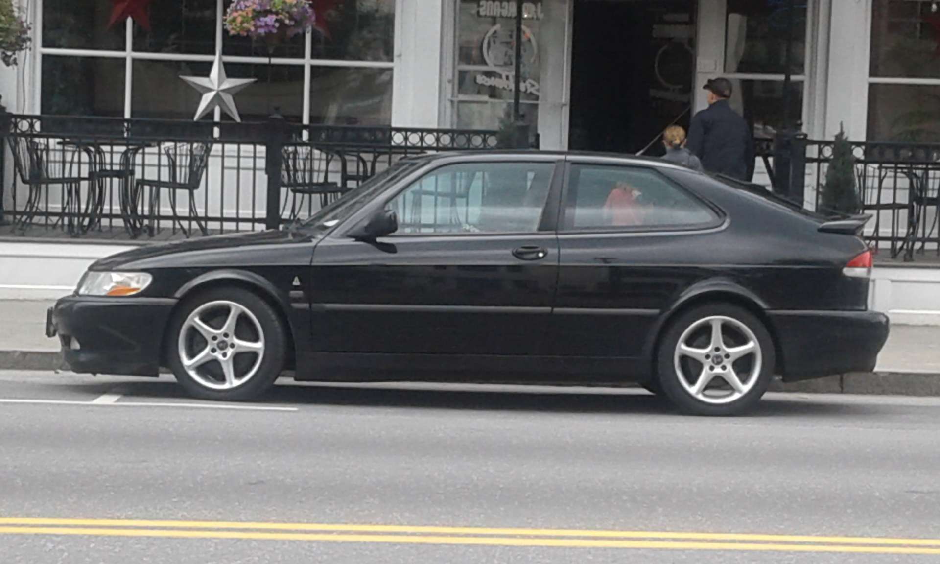 Side profile of a black Saab 9-3 Viggen three-door coupe parked on a street in Montpelier, Vermont, showing the rear spoiler and lowered stance