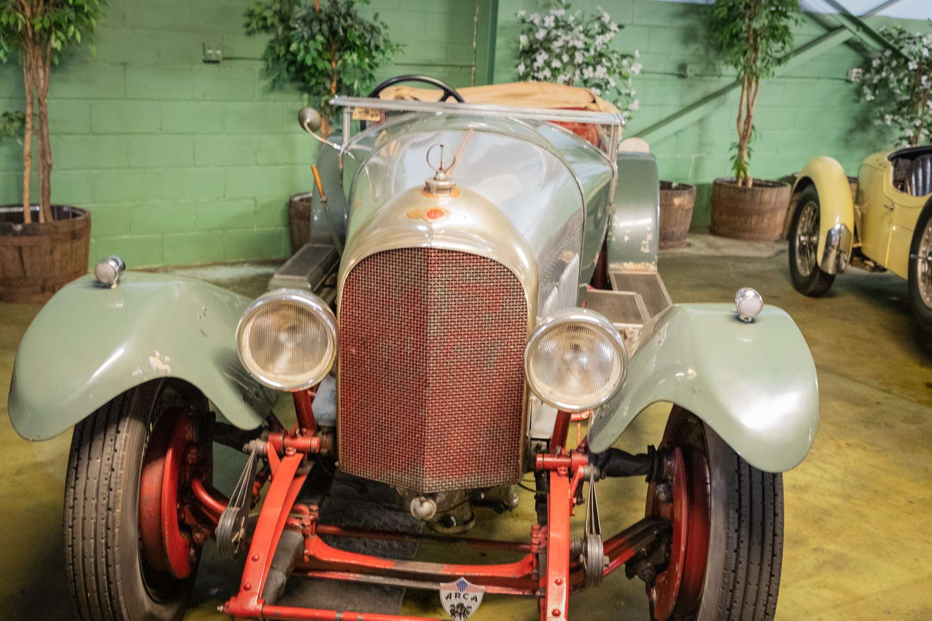 Front view of an unrestored 1927 Bentley 3 Litre Speed Model with red radiator badge background at the Simeone Foundation Automotive Museum