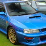 On a Subaru Impreza 22B STi, the Plaque Is Only the Start. The Chassis, Body and Paper Must Agree. Sonic Blue 1998 Subaru Impreza 22B STi coupe from the front three-quarter with bonnet scoop, widened fenders and gold BBS wheels