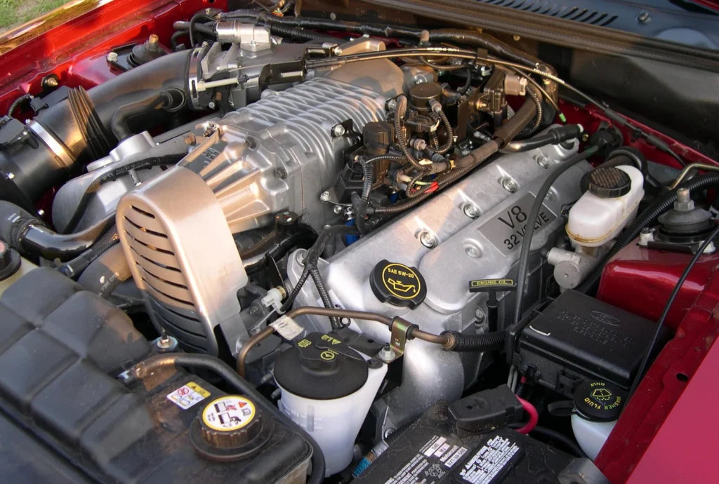Engine bay of a red 2003 Ford Mustang SVT Cobra showing the Eaton-supercharged 32-valve 4.6-liter V8