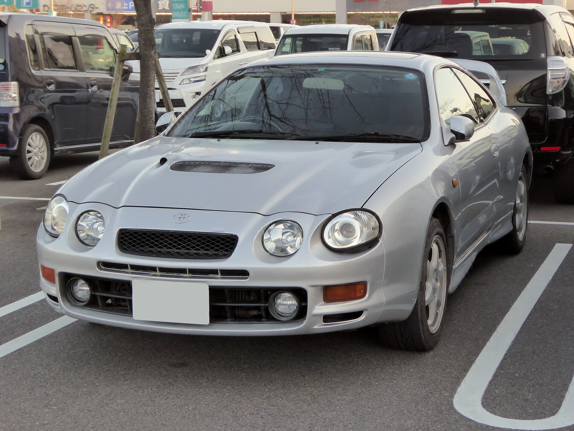 Silver Toyota Celica GT-Four ST205 with hood scoop and round headlights parked in a lot, front view
