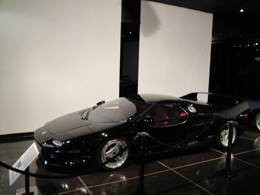 Silver Vector M12 supercar parked outdoors, front three-quarter view
