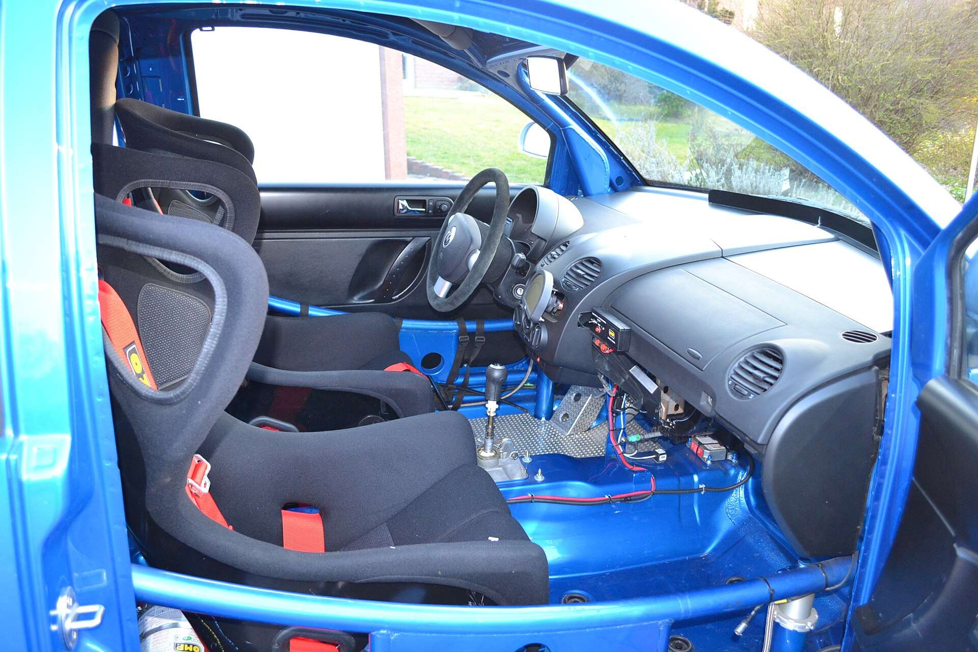 Stripped racing interior of a Volkswagen New Beetle Cup car with bucket seats and a bare blue-painted shell