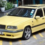 Cream Yellow 1995 Volvo 850 T-5R estate seen from the front three-quarter, showing the lipped front bumper and silver five-spoke alloy wheels